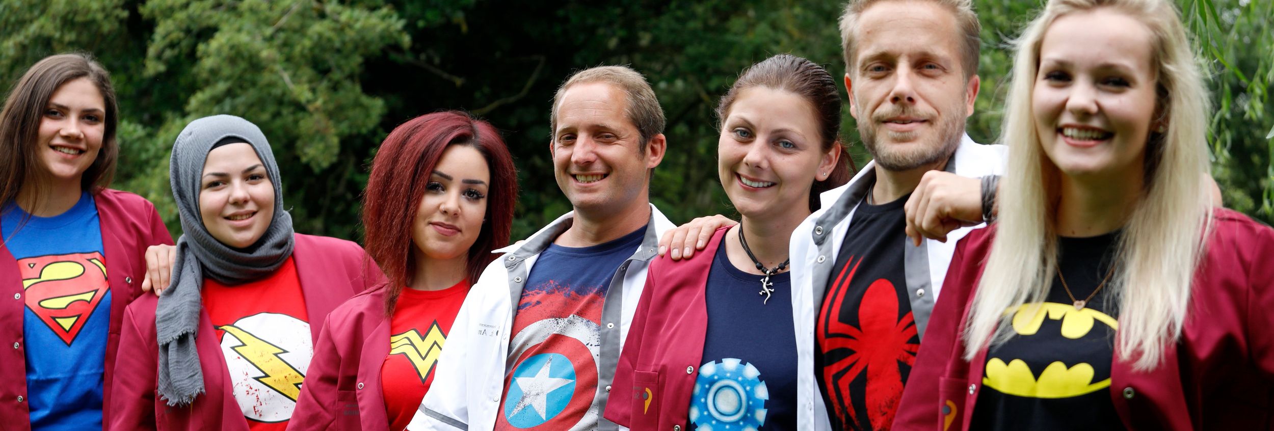 Junge Menschen in Arbeitsjacken mit Superhelden-T-Shirts im Freien