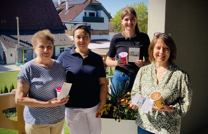 Vier Pflegende auf dem Balkon mit Dankeskarten und kleinen Geschenken