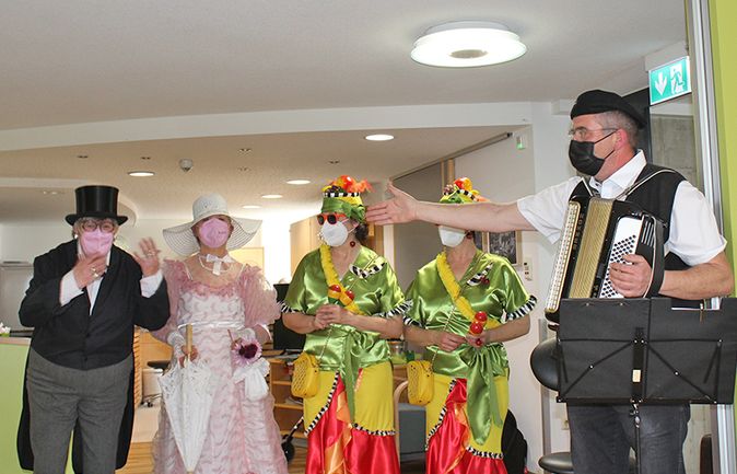 Musiker mit Akkordeon begrüßt kostümierte Personen beim Frühlingsfest