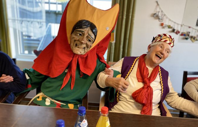 Narrenpaar beim Fasnet mit Holzmaske und Begleitperson im Kostüm