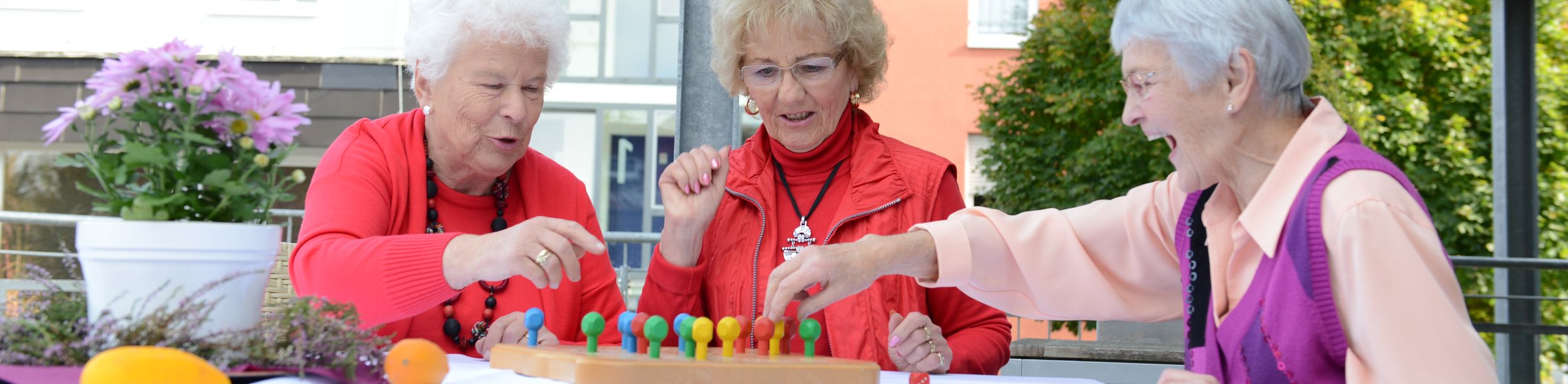Drei ältere Frauen spielen ein Steckspiel am Tisch