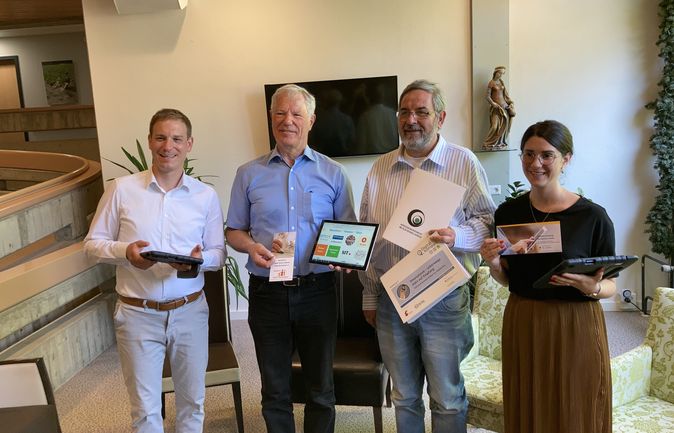 Vier Personen halten Tablets und Schulungsflyer für Tablettraining