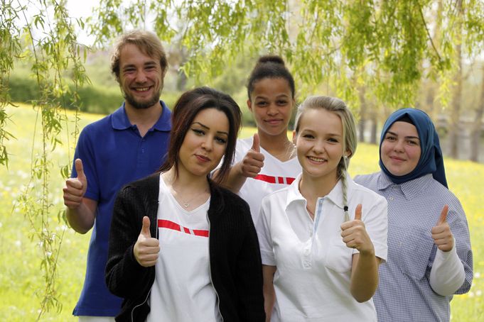 Gruppe junger Menschen lächelnd mit Daumen hoch im Park