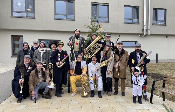 Musikgruppe in Fasnetkostümen mit Blasinstrumenten vor Seniorenzentrum